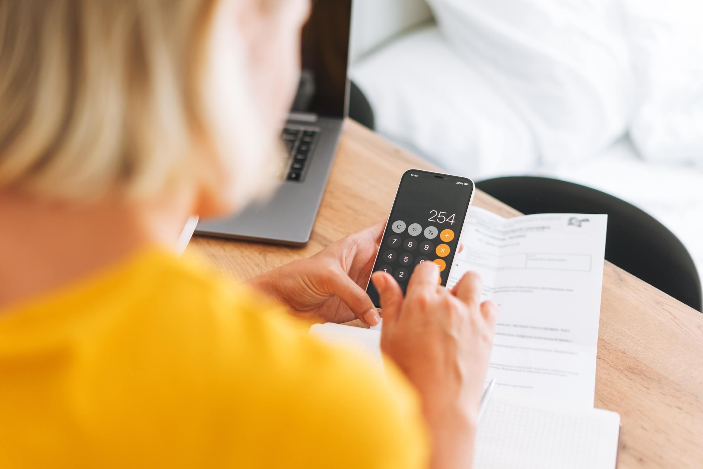 Woman using calculator app on phone to calculate rent price - featured_image