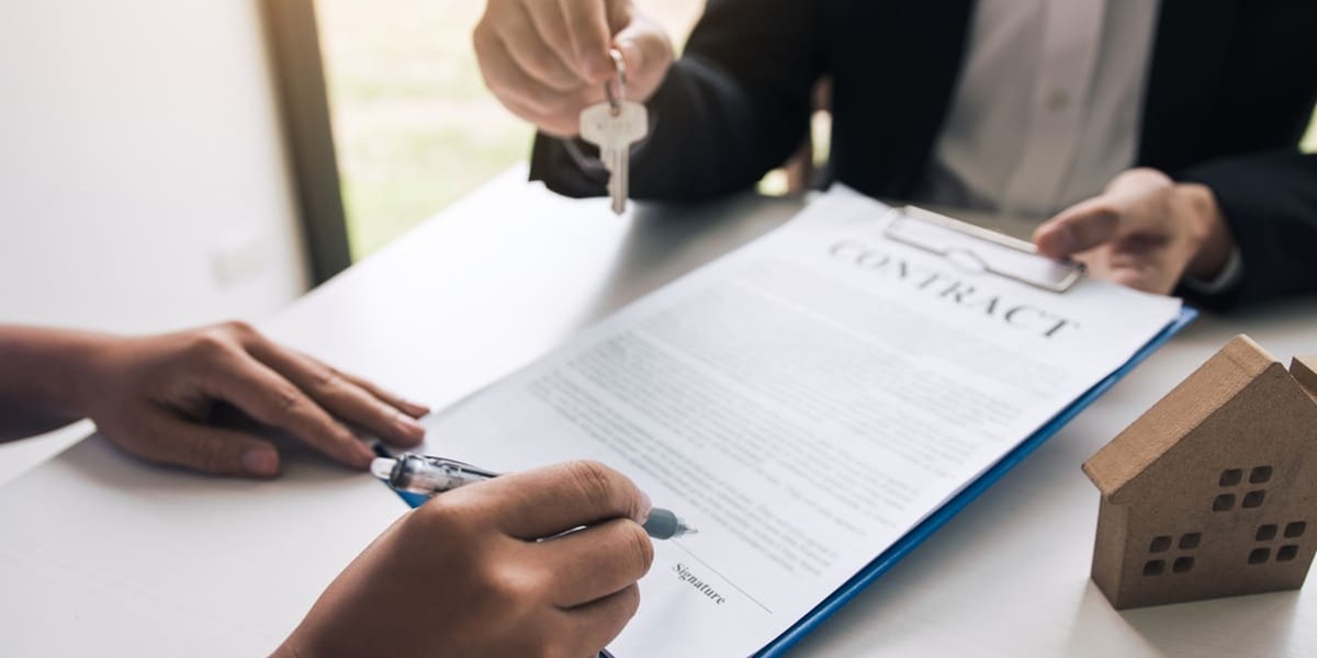 Someone signing a month-to-month lease agreement and a landlord holding keys
