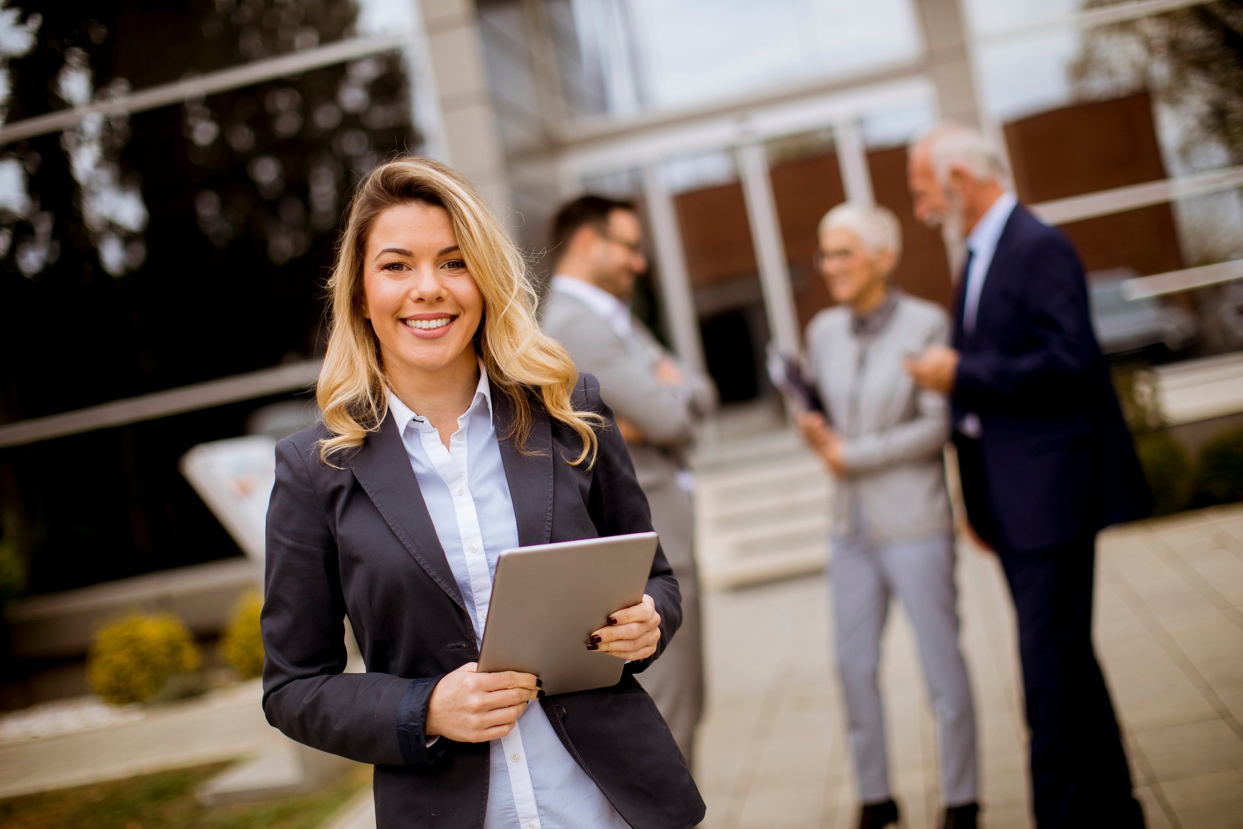 This image features a property manager holding a tablet while other people talk in the background.