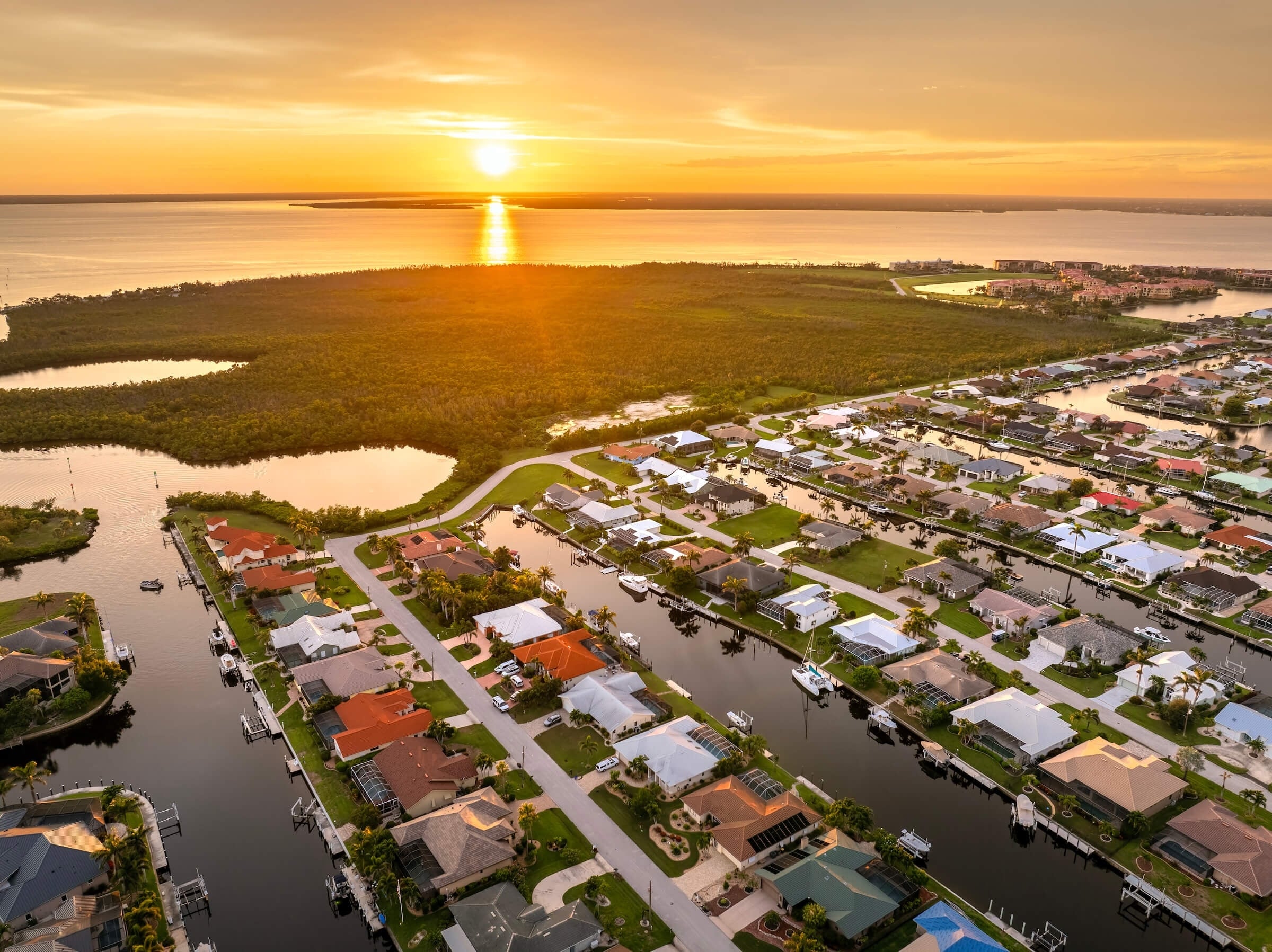 Image of a neighborhood of single family homes with the sun setting over a body of water