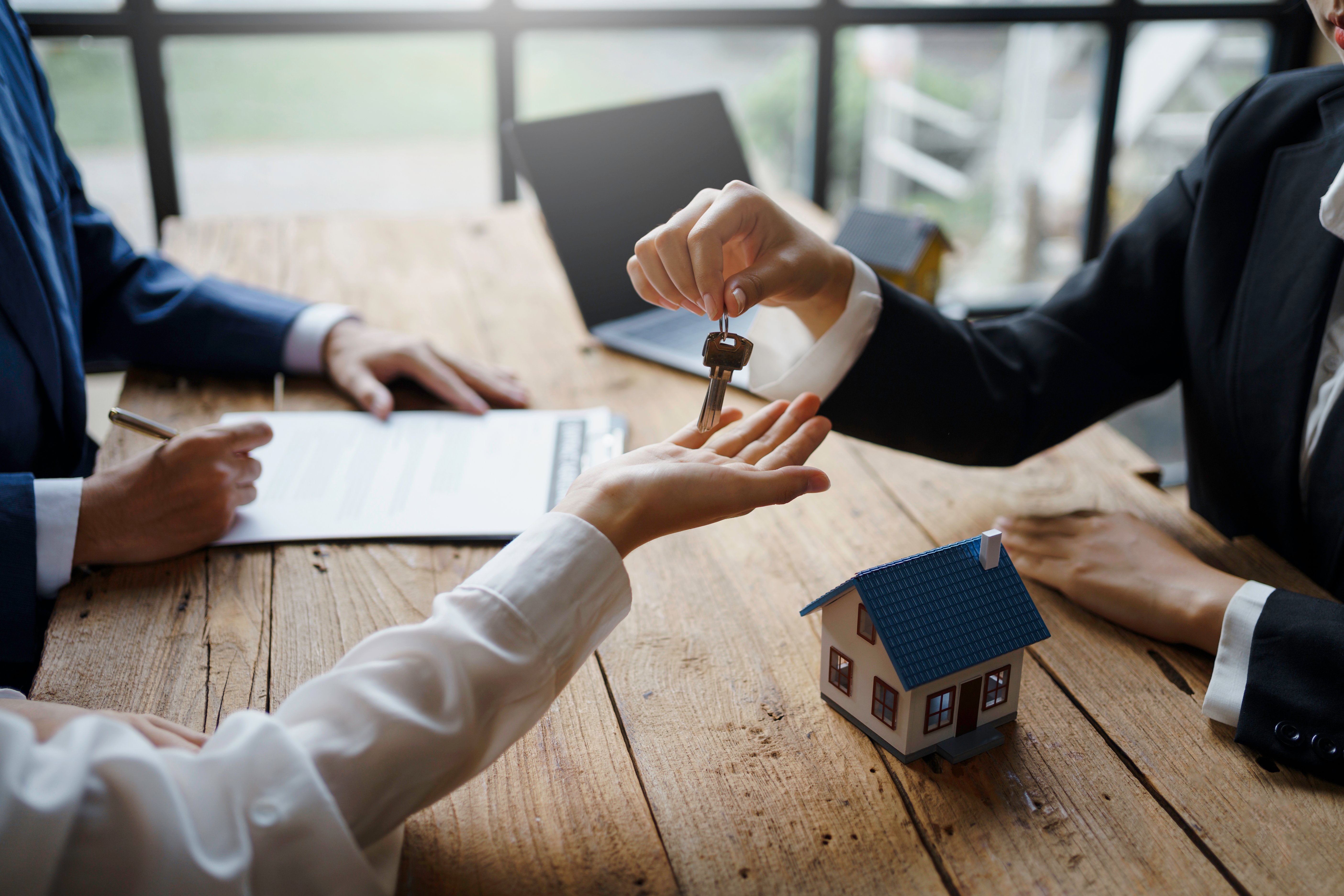 A picture of a property manager and tenant signing contracts and handing over keys. 